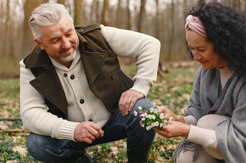 couple collecting wildflowers man and woman squatted down near the ground to pick wildflowers
